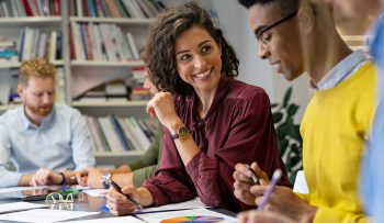 Multiethnic business people discussing together their strategy. Multiethnic business people discussing together their strategy. Happy businesswoman showing marketing strategy african businessman. Creative business team talking and smiling during brainstorming.